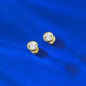 Macro shot of gold-plated S925 silver bezel set round stud earrings with white zircon