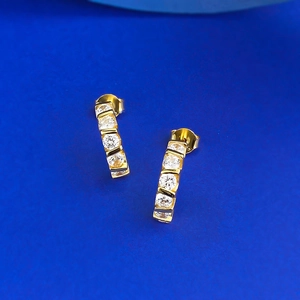 Détail macro de boucles d'oreilles barre dorées avec cinq zircons ronds clairs verticaux