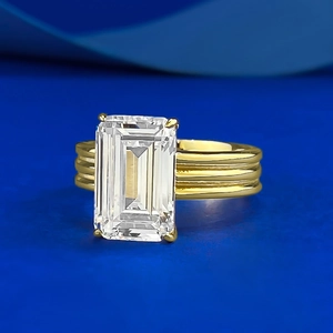 Macro shot of an emerald-cut gemstone ring with a gold-plated triple-band textured design