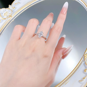 Macro shot of marquise-cut stone ring with retro braided band on mirror background
