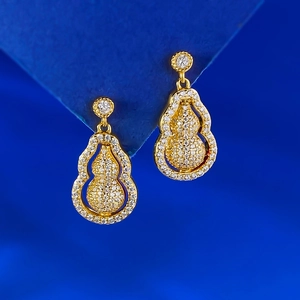 Gros plan sur des boucles d'oreilles gourde pivotantes avec placage or et pavé de zircons fins