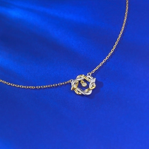 Gros plan du pendentif serpent bicolore avec pierre centrale étincelante sur bleu
