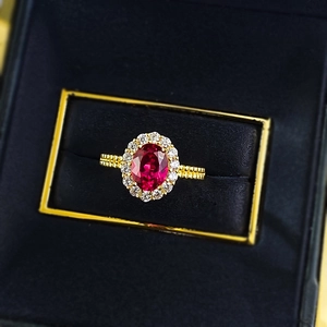 Gros plan d'une bague vintage plaquée or avec pierre rouge ovale et halo de diamants