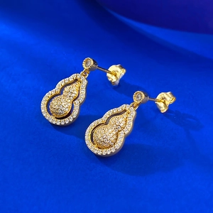 Boucles d'oreilles gourde rotatives en or et zircons blancs sur fond bleu vif