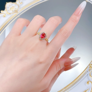 Détail d'une bague halo rubis rouge ovale plaquée or portée par un mannequin
