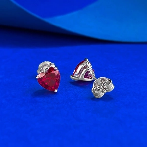 Elegant S925 silver heart earrings with 6mm red ruby stones on a blue textured background