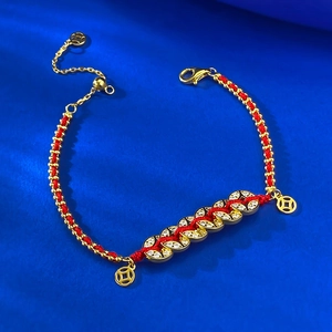 Macro detail of red string bracelet with gold coin charms and sparkling zircons