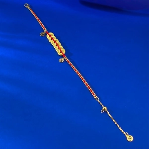 Detail of red braided cord bracelet with five gold coins and adjustable metal chain