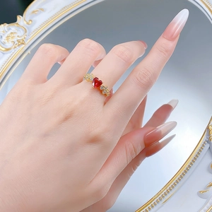 Dettaglio di un anello a cuore d'oro con gemma rossa e diamanti sul dito di una modella