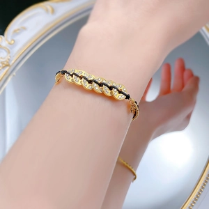 Macro shot of S925 silver five-coin bracelet with gold plating and black braided rope