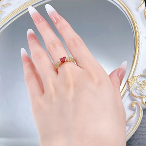 Dettaglio di un anello in argento S925 dorato con gemma rossa a cuore e diamanti laterali