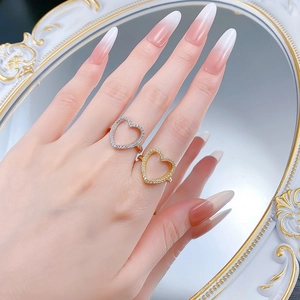Détail de bagues cœur argent et or avec zircons sur main avec de longs ongles manucurés