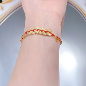 Close-up of red cord bracelet with gold coin charms and sparkling zircon inlay