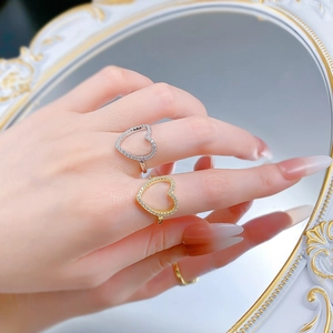 Détail de bagues en argent S925 en forme de cœur évidé avec pavé de zircons en or et argent