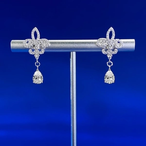 Detail of S925 silver fleur-de-lis earrings with a pear-shaped drop stone on a stand