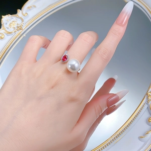 Close-up of S925 silver ring featuring red gemstone and large pearl on a model's finger