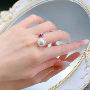 Detail of S925 silver open ring featuring a white pearl and red ruby stone on finger