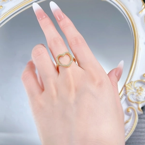 Gros plan d'une bague coeur dorée avec cristaux pavés portée sur la main