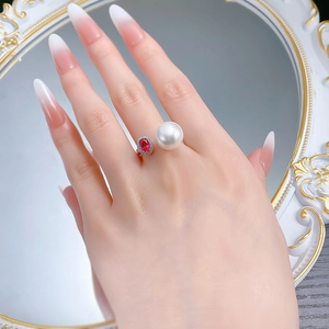 Close-up of S925 silver ring with large white pearl and ruby zircon on a model's hand