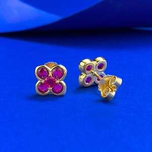 Elegant gold S925 silver four-leaf clover stud earrings with red gemstones on blue background