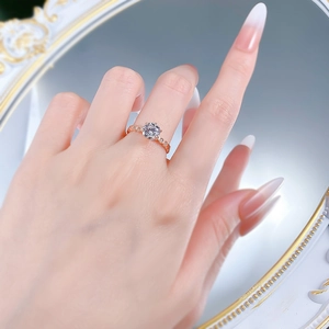 Rose gold six-prong solitaire ring with side diamonds shown on model finger