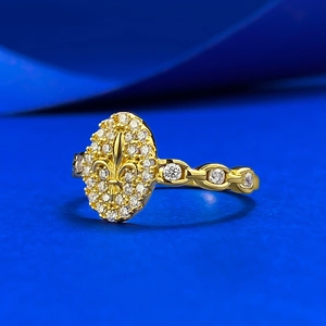Detailed macro shot of a gold fleur-de-lis ring featuring pave zircons and hollow band