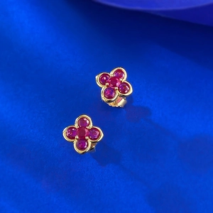 Macro detail of red ruby gemstone clover flower earrings in a polished gold setting