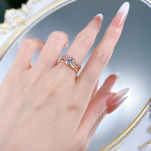 Detailed view of rose gold six-prong round diamond ring and honeycomb pavé bands on a hand