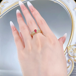 Detail of vintage 18K gold ring with oval red ruby and white zircon stones on finger