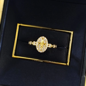 Detailed view of an oval fleur-de-lis ring with pavé-set stones in a luxury gift box