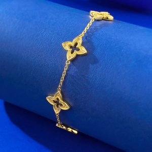 Détail d'un bracelet trèfle doré avec breloques évidées et zircons brillants étincelants