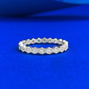 Detailed view of silver honeycomb eternity ring with sparkling cubic zirconia on blue surface