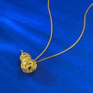 Detail of a hollow gold filigree gourd pendant necklace on textured dark blue fabric