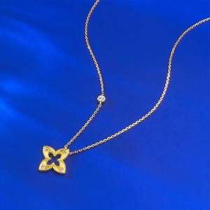 Détail d'un pendentif trèfle doré avec bordure perlée sur un tissu en soie bleu foncé