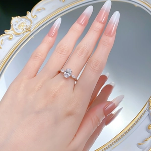 Detailed view of an oval three-stone silver ring worn on a finger with a mirror reflection