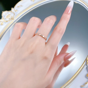 Macro shot of rose gold honeycomb ring with small diamonds on hand before a mirror