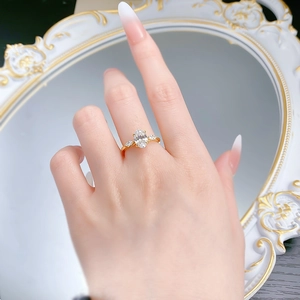 Vista macro di un anello dorato con pietra ovale e tre pietre indossato da una modella