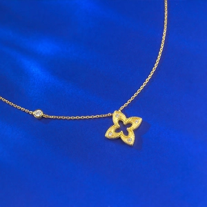Élégant collier trèfle doré avec diamants sur fond de tissu bleu texturé brillant