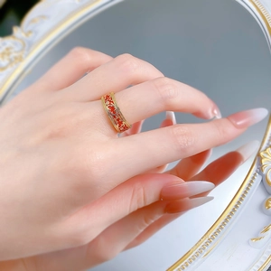Detail of vintage gold ring with red enamel floral pattern worn on finger