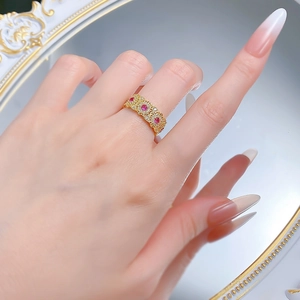 Detailed shot of golden vintage openwork ring with red gemstones on hand
