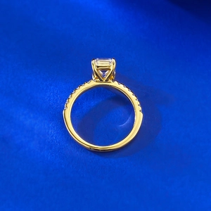 Elegant 18K gold ring with emerald cut crystal and pavé set diamonds on a blue background