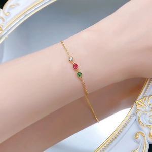 Gros plan détaillé d'un bracelet délicat en or orné de pierres rouges vertes et blanches