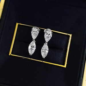 Macro shot of S925 silver earrings with pear and marquise cut zircon on blue velvet