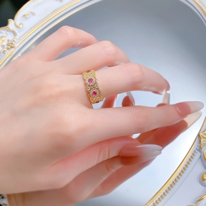 Macro detail of vintage hollow gold ring with red gemstones and sparkling white diamonds