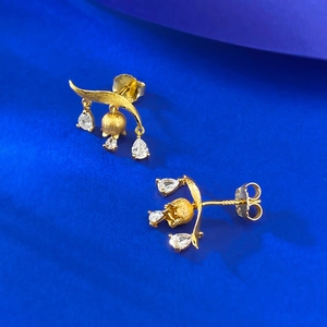 Golden lily of the valley earrings with teardrop zircon on a bright blue background