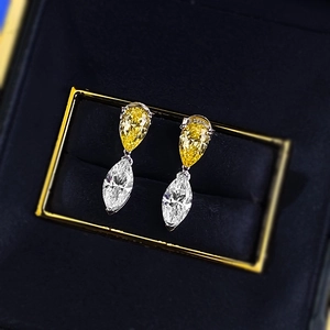 Macro view of teardrop and marquise cut yellow and white zircon earrings in a blue box
