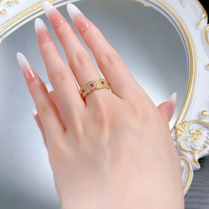 Macro detail of gold vintage镂空ring with three red gemstones and micro-pave diamonds