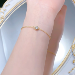 Gros plan d'un bracelet solitaire doré de 6 mm sur le poignet d'une femme