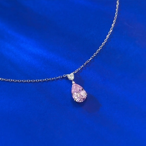 Macro shot of a pear-shaped pink gemstone pendant with a heart-shaped accent on silver chain