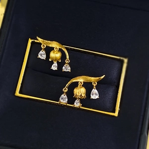 Macro shot of lily of the valley earrings with gold brushed texture and zircon droplets